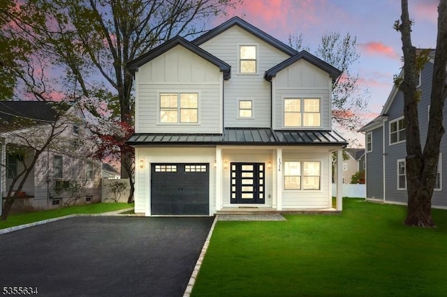 modern home featuring board and batten siding, a standing seam roof, aphalt driveway, and a front lawn
