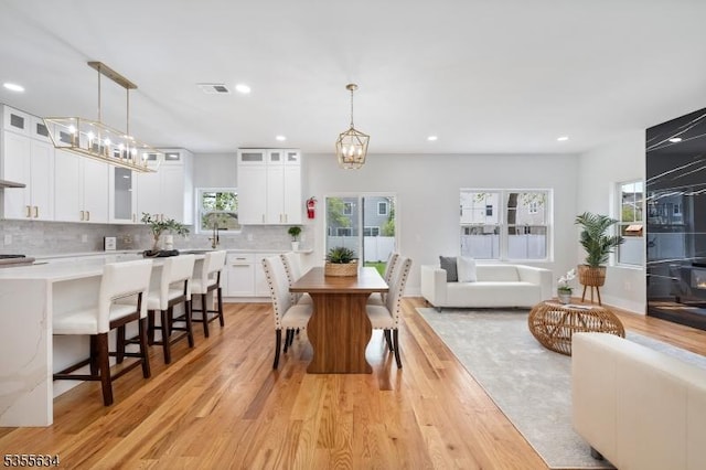 dining space featuring light wood-type flooring, visible vents, and a notable chandelier