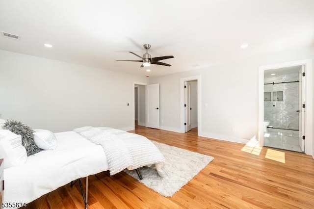 bedroom featuring connected bathroom, a ceiling fan, visible vents, baseboards, and light wood-style floors