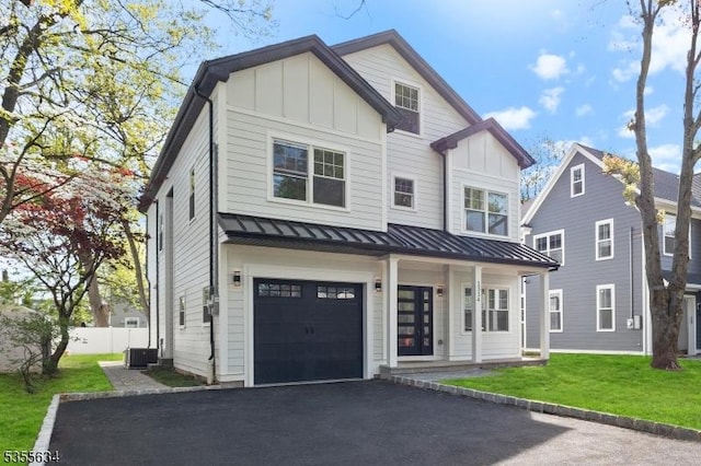modern farmhouse featuring a front yard, an attached garage, a standing seam roof, and board and batten siding