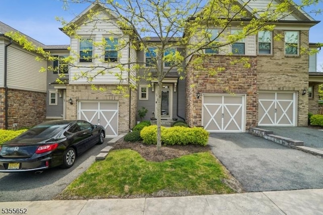 view of property featuring an attached garage, brick siding, and driveway