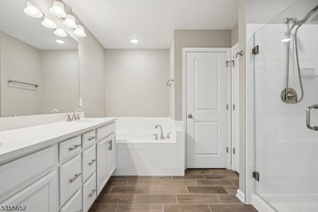 bathroom featuring wood tiled floor, a garden tub, vanity, and a stall shower
