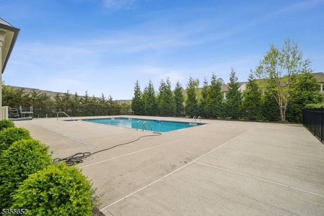 community pool with a patio area and fence