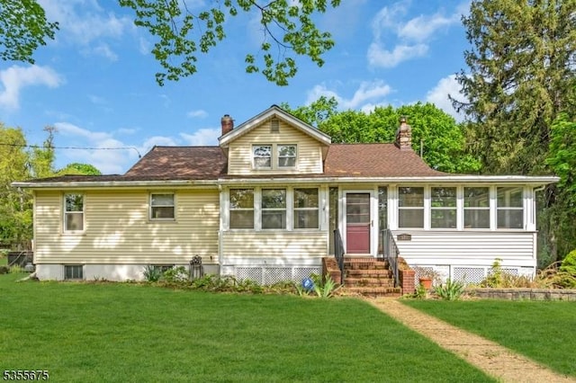 view of front of property with entry steps, a chimney, and a front lawn