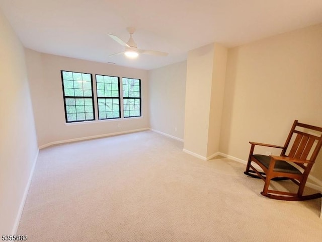 living area with light carpet, ceiling fan, and baseboards