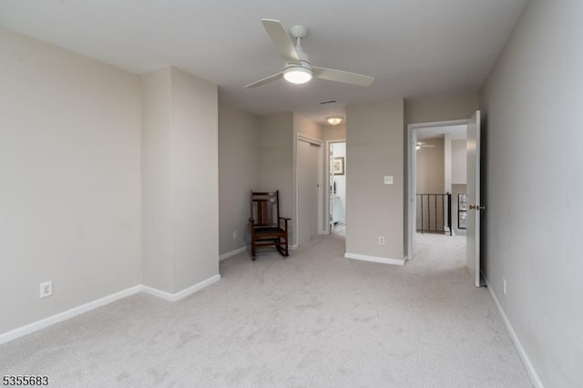 spare room featuring ceiling fan, light carpet, and baseboards