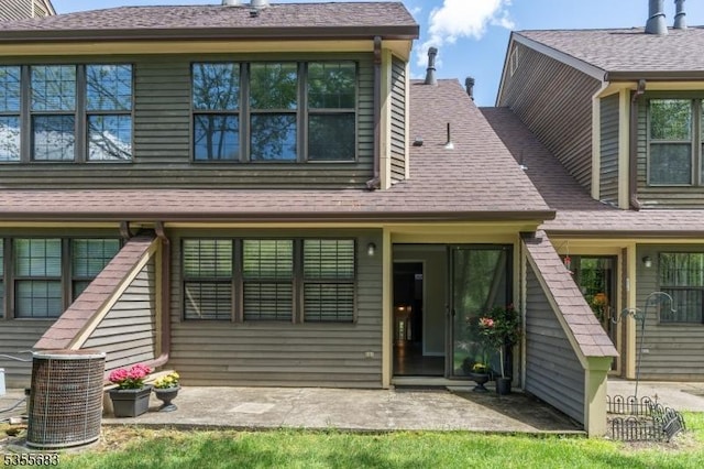 view of front of house with central AC, a patio, and a shingled roof