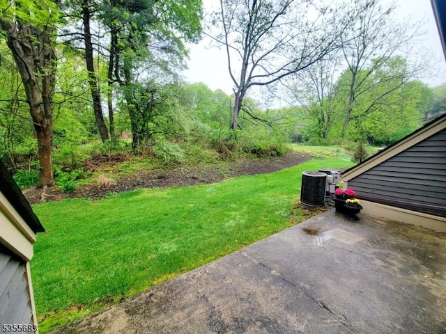 view of grassy yard featuring central air condition unit and a patio
