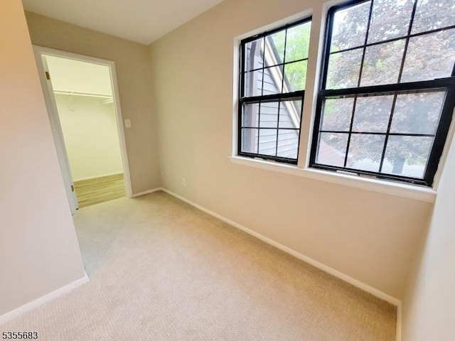 unfurnished bedroom with light carpet, baseboards, a spacious closet, and a closet