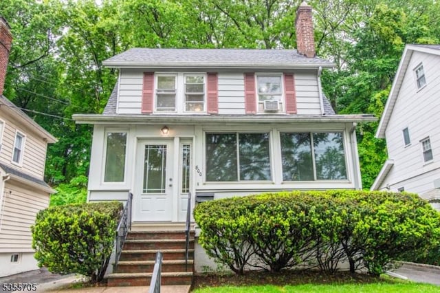 american foursquare style home with a chimney, cooling unit, and entry steps