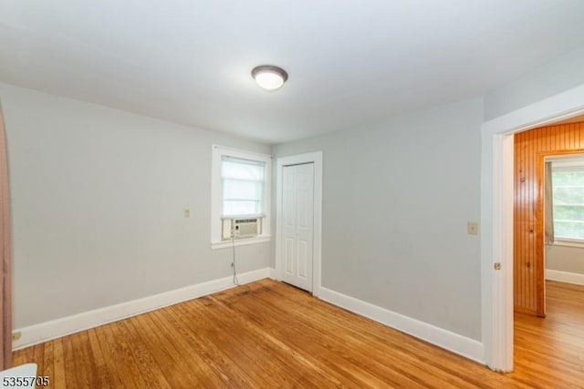 unfurnished room with light wood finished floors, baseboards, and cooling unit