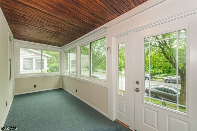 unfurnished sunroom with wooden ceiling, plenty of natural light, baseboards, and carpet