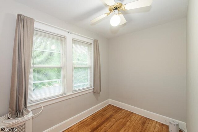 unfurnished room with baseboards, light wood finished floors, and a ceiling fan
