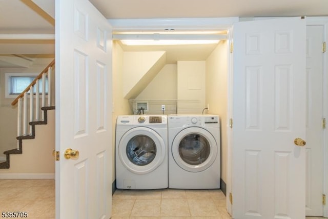 washroom with separate washer and dryer, light tile patterned floors, and baseboards