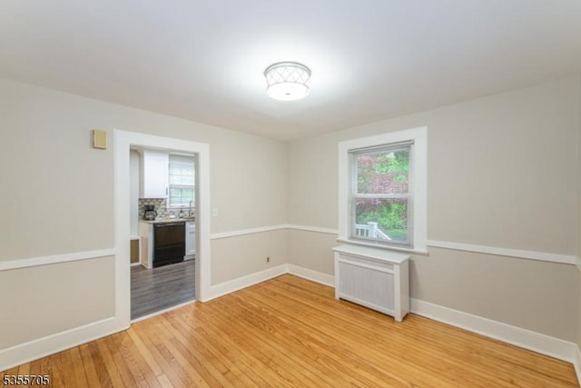 spare room with light wood finished floors, radiator heating unit, and baseboards