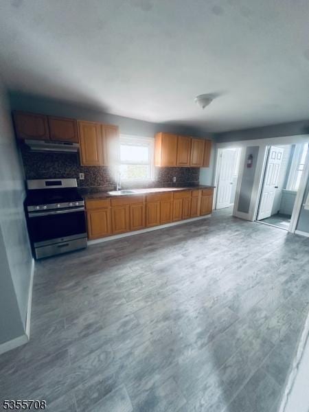 553-555 S 10th St, Newark City, NJ 07103 - kitchen featuring stainless steel electric stove, under cabinet range hood, baseboards, decorative backsplash, and brown cabinets
