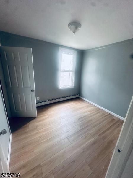 553-555 S 10th St, Newark City, NJ 07103 - unfurnished bedroom with a baseboard radiator, light wood-type flooring, and baseboards
