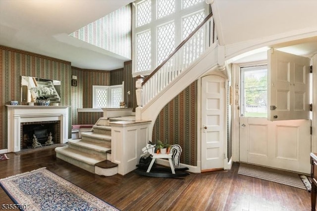 197 Nutley Ave, Nutley Twp, NJ 07110 - entryway with wallpapered walls, arched walkways, dark wood-style flooring, stairs, and a fireplace