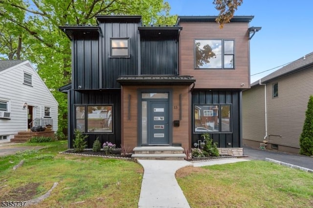 contemporary home featuring board and batten siding and a front lawn