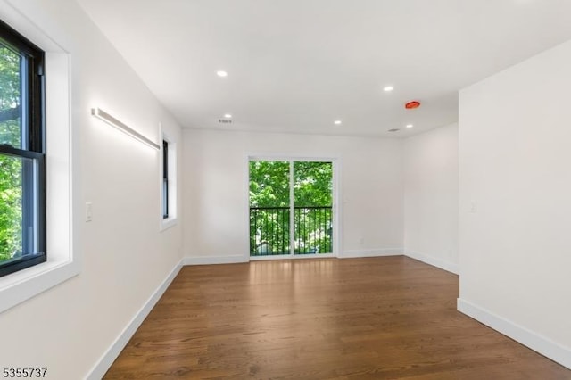 empty room with wood finished floors, baseboards, and recessed lighting