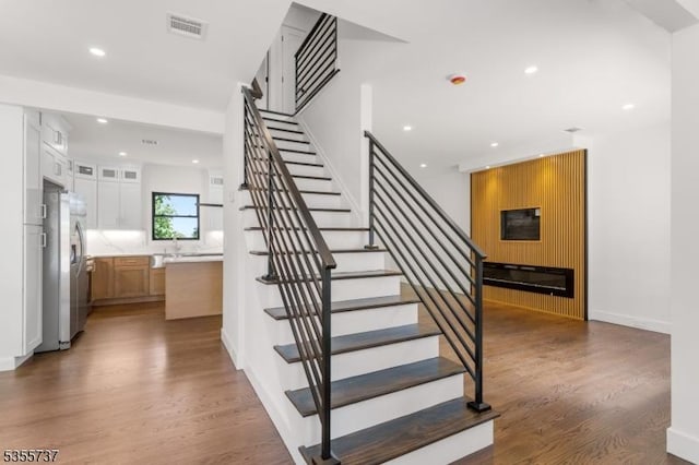 staircase with wood finished floors, recessed lighting, and baseboards