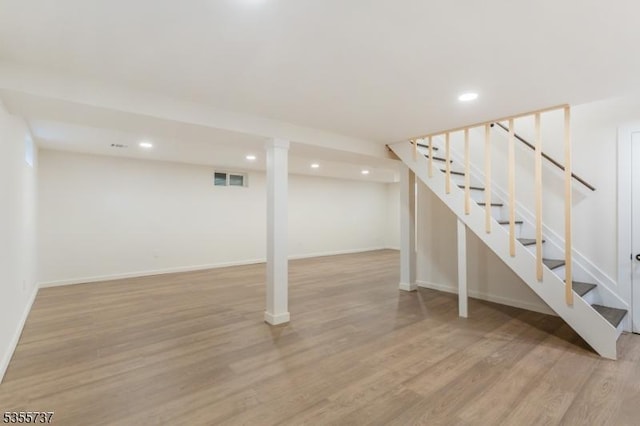 finished below grade area with stairs, recessed lighting, light wood-type flooring, and baseboards