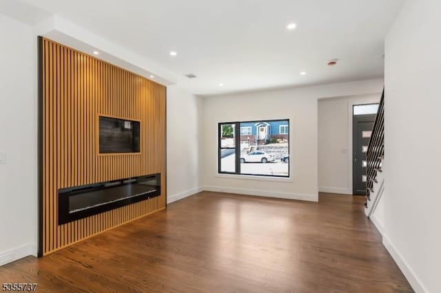 unfurnished living room with wood finished floors, stairway, recessed lighting, and baseboards