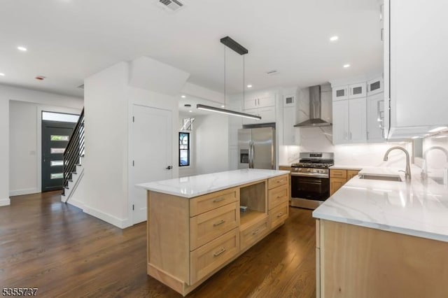 kitchen featuring appliances with stainless steel finishes, wall chimney range hood, a sink, dark wood-type flooring, and a kitchen island
