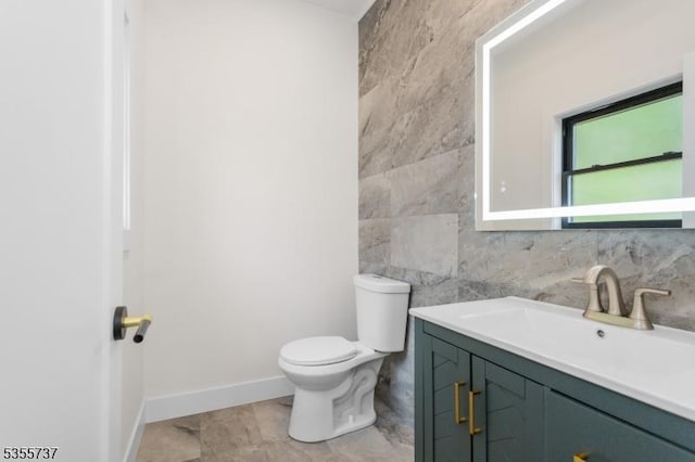 bathroom featuring tile walls, toilet, vanity, and baseboards