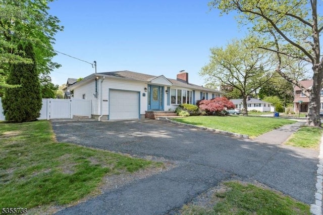 single story home with an attached garage, asphalt driveway, a chimney, and a gate