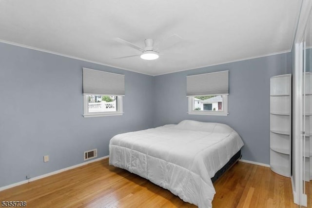 bedroom featuring wood finished floors, baseboards, crown molding, and ceiling fan