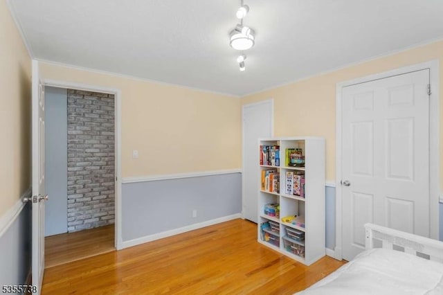 bedroom featuring wood finished floors, ornamental molding, and baseboards