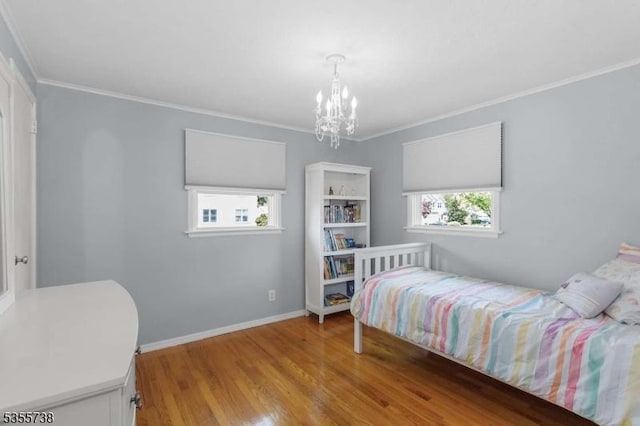 bedroom featuring wood finished floors, ornamental molding, a chandelier, and baseboards