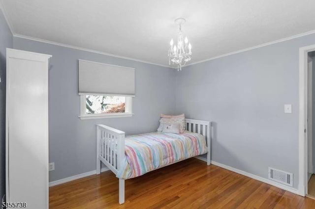 bedroom with wood finished floors, a chandelier, baseboards, and ornamental molding