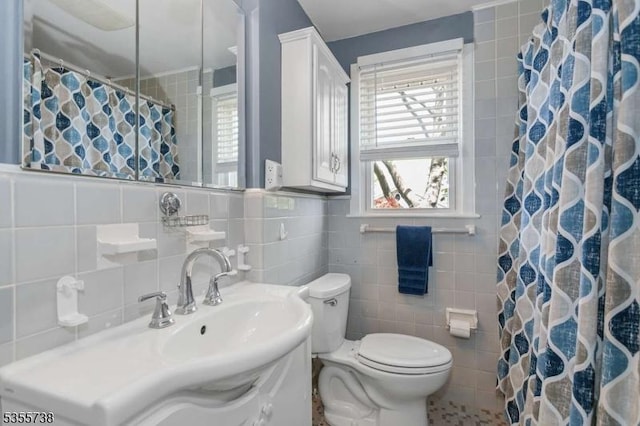 bathroom with tile walls, toilet, a shower with curtain, and vanity