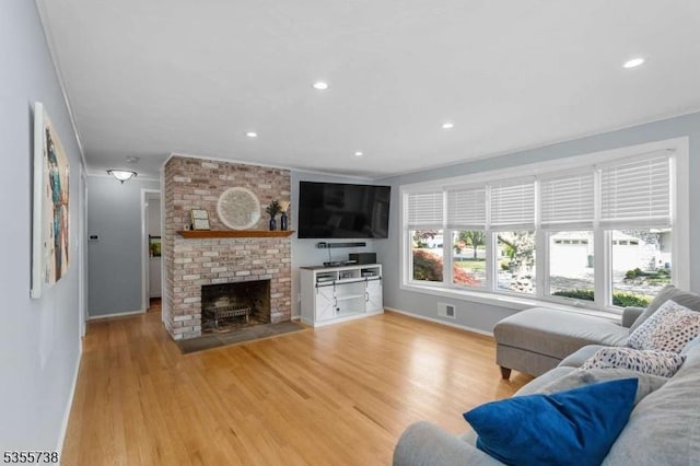 living room featuring baseboards, light wood finished floors, a fireplace, recessed lighting, and crown molding