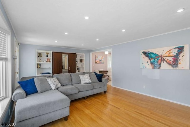 living area featuring light wood-style floors, recessed lighting, crown molding, baseboards, and built in shelves