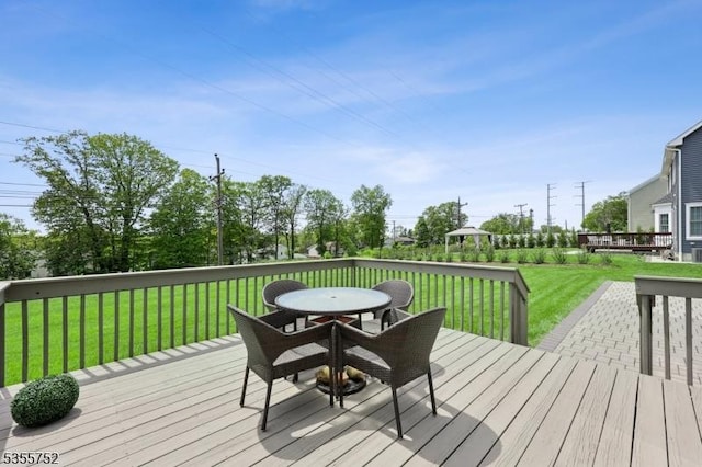 wooden terrace with outdoor dining area and a lawn