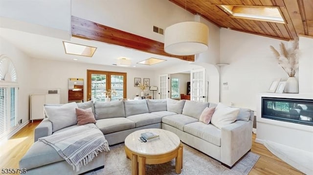 living room with light wood finished floors, french doors, vaulted ceiling with skylight, visible vents, and wooden ceiling