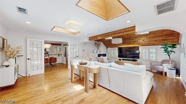 living area featuring light wood-style floors, visible vents, arched walkways, and recessed lighting