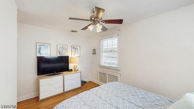bedroom featuring baseboards, light wood-style floors, visible vents, and a ceiling fan