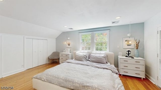 bedroom featuring vaulted ceiling, a closet, visible vents, and wood finished floors