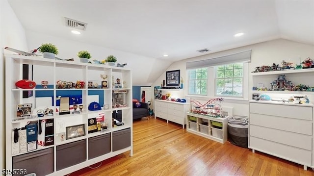 rec room featuring wood finished floors, visible vents, and vaulted ceiling