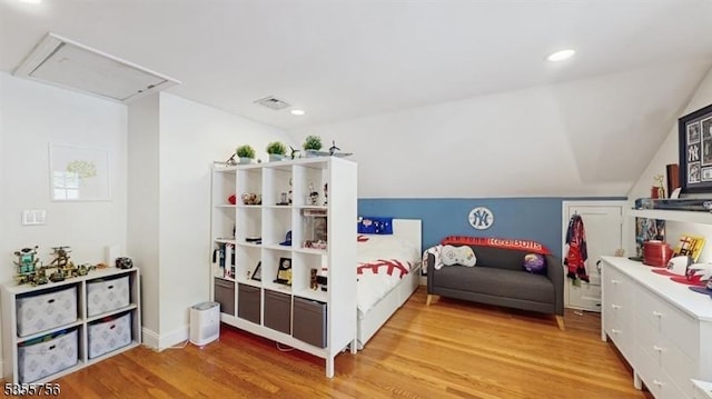bedroom featuring vaulted ceiling, attic access, light wood-style floors, and visible vents