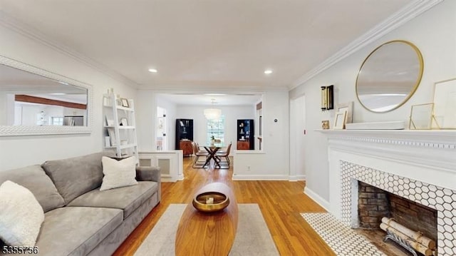 living area featuring a tile fireplace, wood finished floors, ornamental molding, and recessed lighting