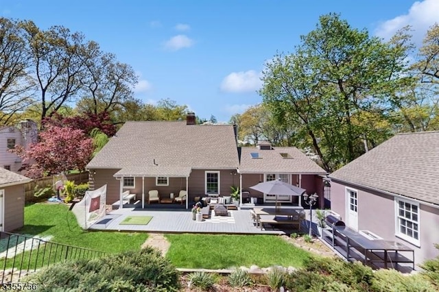 back of property with a chimney, a lawn, a wooden deck, a fenced backyard, and an outdoor living space