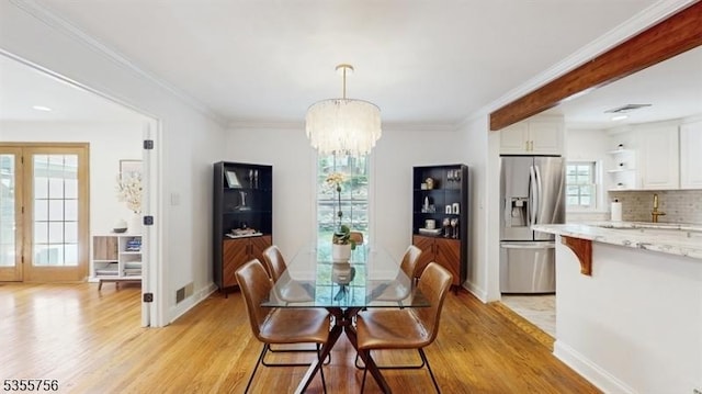 dining room featuring baseboards, crown molding, an inviting chandelier, and light wood-type flooring