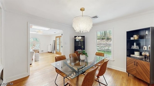 dining area with ornamental molding, light wood-type flooring, visible vents, a notable chandelier, and baseboards