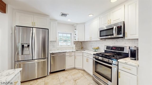 kitchen with white cabinetry, appliances with stainless steel finishes, tasteful backsplash, and a sink