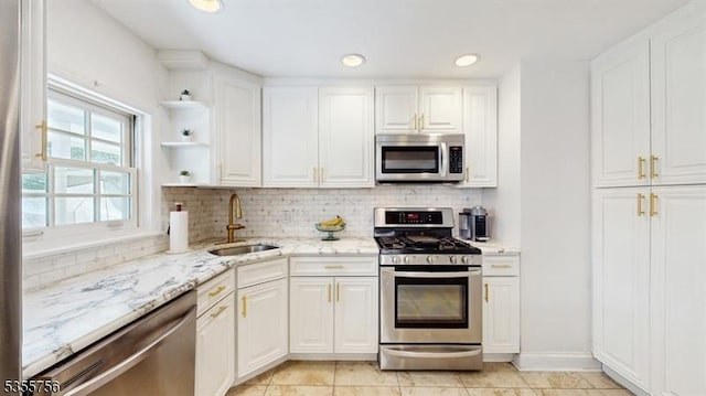 kitchen with a sink, white cabinetry, backsplash, and appliances with stainless steel finishes